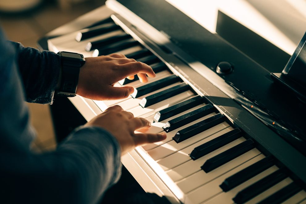 A piano student practicing on a digital keyboard at home
